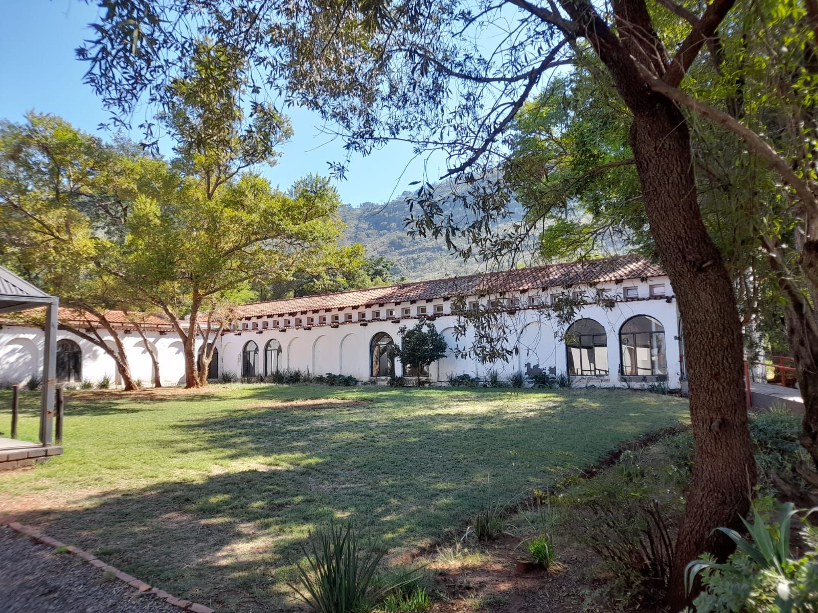 The whitewashed courtyard and arched buildings at Aloe Valley with the Magaliesberg behind