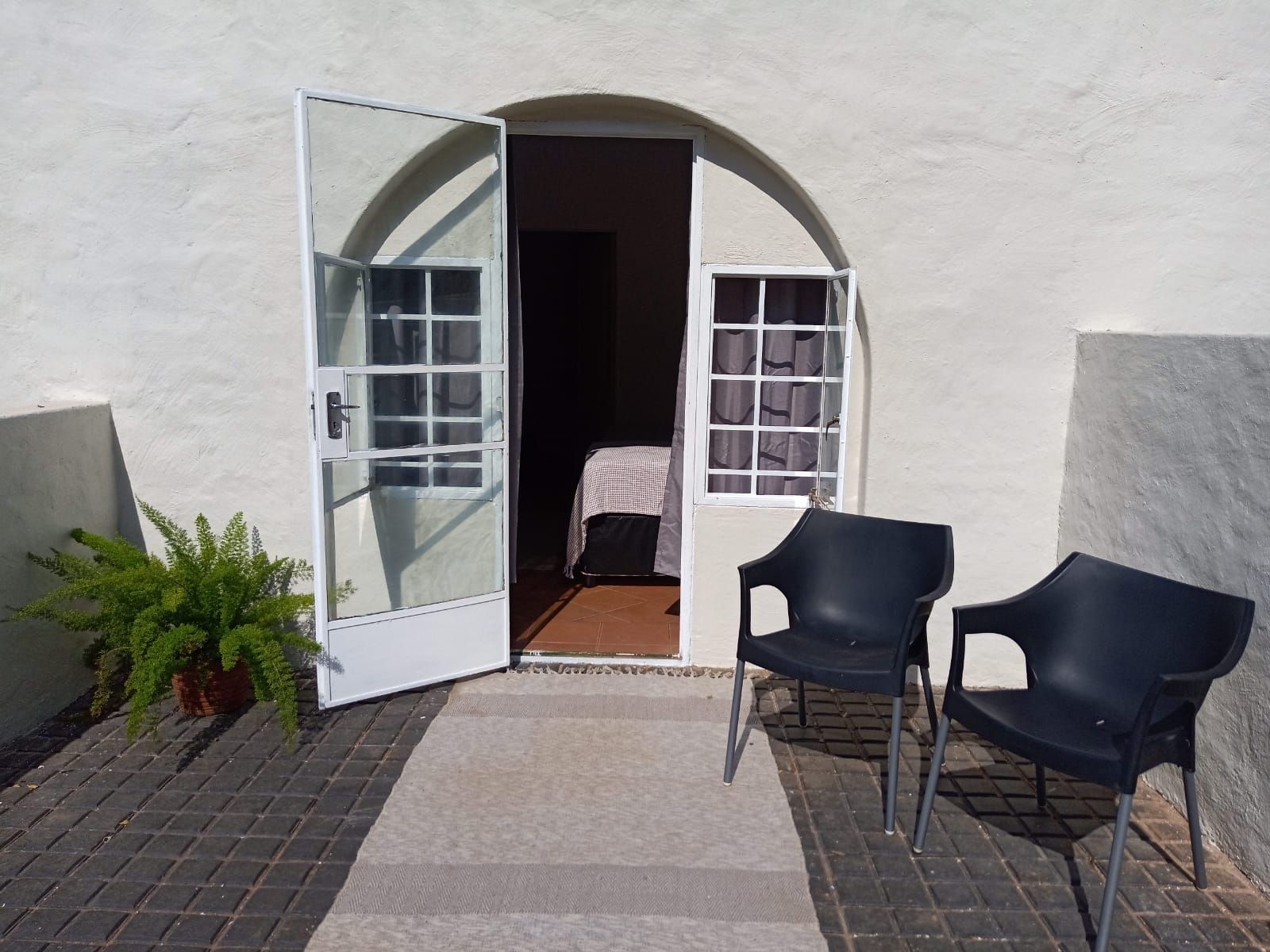 A private patio outside an en-suite room, with an arched door and two chairs